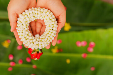 Mother's hand holding a jasmine garland during Songkran Festival