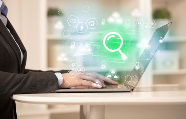 Hands working on laptop with digital icons