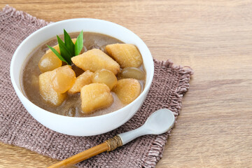 Kolak, Kolak Pisang is Indonesian traditional dessert, very popular during Ramadhan, made from banana with coconut milk, sugar and pandanus leaves. Served in white bowl on wooden table.

