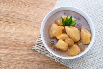 Kolak, Kolak Pisang is Indonesian traditional dessert, very popular during Ramadhan, made from banana with coconut milk, sugar and pandanus leaves. Served in white bowl on wooden table.
