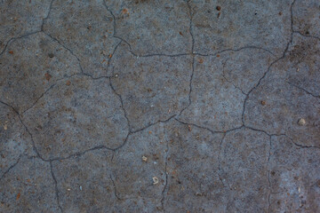 Texture of the dried earth. Dark gray background with cracks and hollows. Drought and lack of moisture in the soil. The consequences of abnormal heat. Environmental disaster. Global warming.