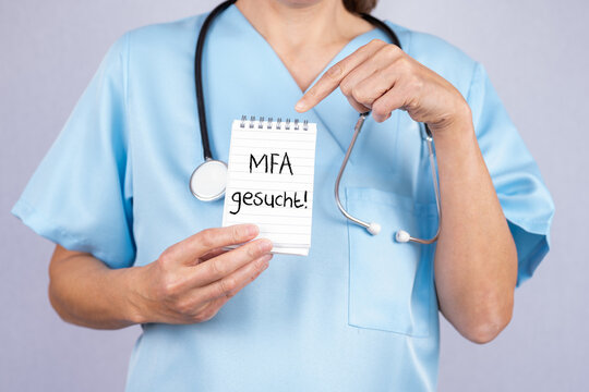 Arzthelferin zeigt auf einen Notizblock auf dem MFA  gesucht steht