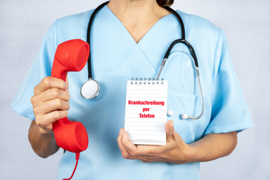Eine Ärztin oder MFA mit einem roten Telefonhörer und einem Notizblock auf dem Krankschreibung per Telefon steht