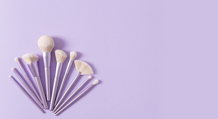 Makeup brushes banner. Set of glamour makeup brushes on violet background. Magazines, social media. Visagist tools. Top view, copy space. Creative flat lay. Cosmetics products web line, sale