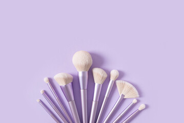 Professional makeup tools brushes on a pastel violet background. Set of glamour makeup brushes. Magazines, social media. Visagist tools. Top view, copy space. Creative flat lay. Cosmetics products
