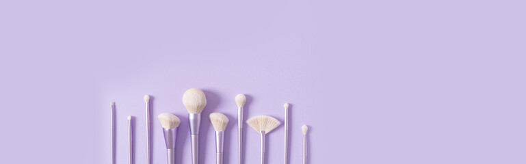 Makeup brushes banner. Set of glamour makeup brushes on a pastel violet background. Magazines, social media. Visagist tools. Top view, copy space. Creative flat lay. Cosmetics products web line, sale