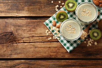 Flat lay composition with tasty kiwi oatmeal smoothie on wooden table. Space for text