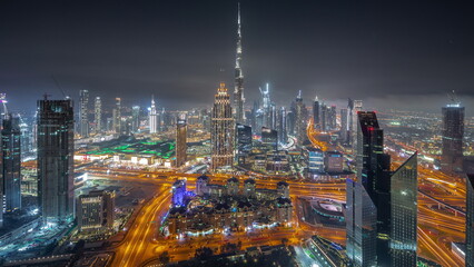 Fototapeta premium Aerial view of tallest towers in Dubai Downtown skyline and highway all night timelapse.