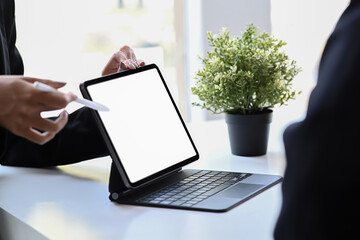 Cropped shot businesswoman showing digital tablet for sharing ideas or startup business plan with business partner.