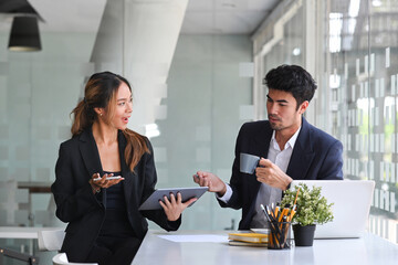 Attractive coach leader sharing ideas or startup business plan with her colleague.