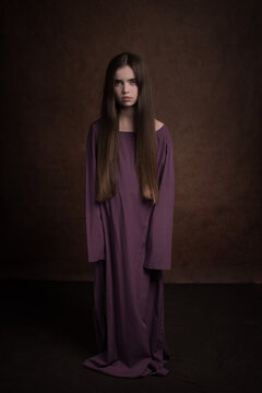 Classic painterly dark studio portrait of a girl in a dress