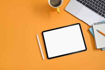 Digital tablet, stylus pen, laptop, coffee cup and notebook on yellow background. Flat lay.