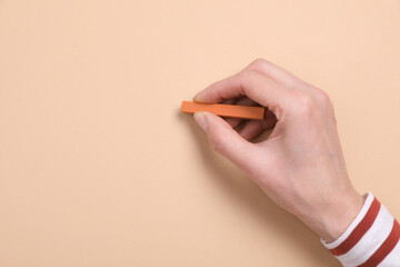 Woman drawing on beige paper with pastel, top view. Space for text