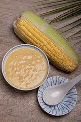 Sweet corn soup in a ceramic cup on wooden background.
