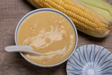 Sweet corn soup in a ceramic cup on wooden background.