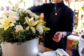 Florist at work: young women making fashion modern bouquet of different flowers. A girl florist makes a beautiful, fresh, blossom bouquet of colorful flower at flower shop.