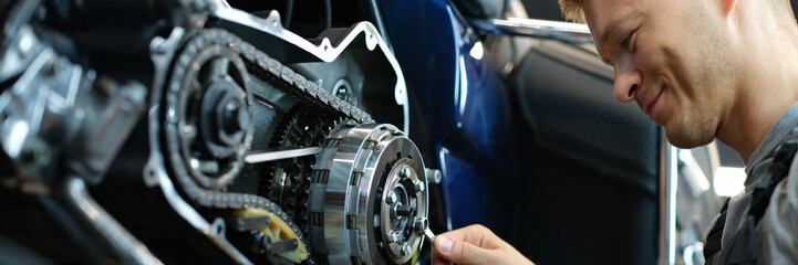 Master repairing motorcycle in workshop using wrench