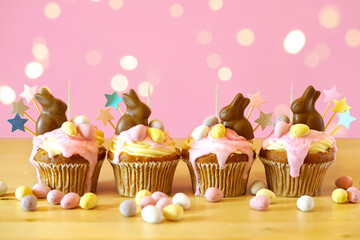 Easter cupcakes topper mockups decorated with chocolate bunnies in party table setting with bokeh...
