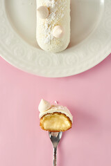 Sliced eclair with custard on a pink background
