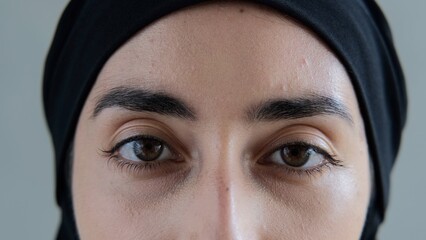 Close-up of brown eyes with black eyebrows look into the frame so deeply that they look into your...