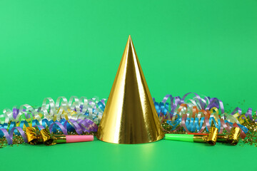 Colorful serpentine streamers, party cap and horns on green background