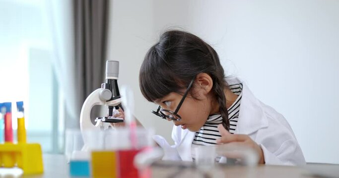 Lovely girl in eyeglasses smile with happy, use microscope, laptop computer and device of experimenting with liquids on table, while studying science chemistry, selective focus