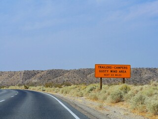 Scenic road view along Interstate 15 with a roadside sign warning trailers and campers of gusty wind in California.