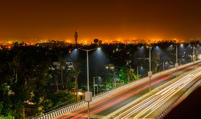 Night highway with car traffic, lights trails and city lights when long exposure, soft focus
