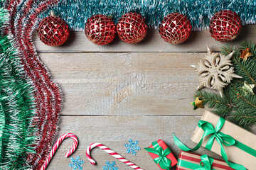Frame of bright tinsel and Christmas decor on wooden background, flat lay. Space for text