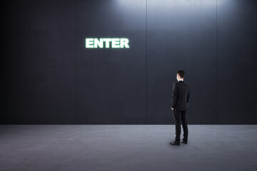 Obraz premium Thoughtful young businessman standing in concrete interior with entrance to success. Way and opportunity concept.