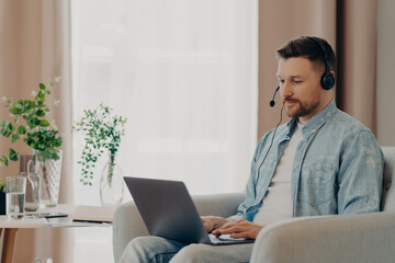 Calm freelancer enjoying his job online while looking at laptop screen