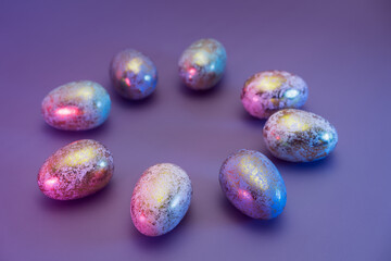 Side view round frame made of Easter golden eggs with different patterns in neon colors light. Purple very peri color minimalist festive background. Modern trendy Easter. Selective focus. Copy space.