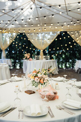 Evening decoration of a wedding party. Tables for guests with a garland and lamps