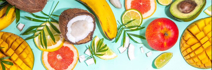 Summer fruits background. Various tropical fruits on turquoise background - mango, coconut, apples, avocado, lemon, orange, grapefruit, pineapple, with palm leaves. Colorful frame, banner flatlay