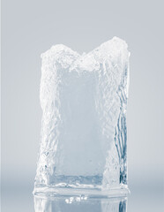Crystal clear, pure ice block, on a light blue surface with reflection. A big piece of ice.