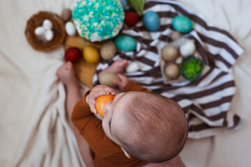 Happy Easter. Cute and happy little baby playing with Easter eggs and cake at home.