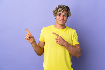 English man over isolated purple background frightened and pointing to the side © luismolinero