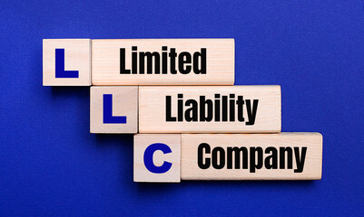 On a bright blue background, light wooden blocks and cubes with the text LLC Limited Liability Company