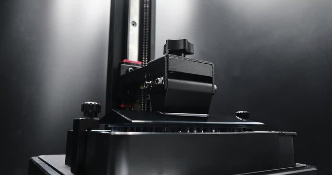 Time lapse 3D printer printing the word 3D printing  form liquid resin using MSLA or Masked Stereolithography. Side view low angle Time lapse of consumer resin MSLA 3d printer, additive manufacturing.