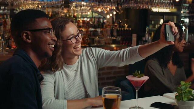 Diverse group of friends taking selfies in restaurant together