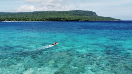 A small red motorboat in stunning crystal clear ocean water near Jaco Island, Timor Leste, Southeast Asia