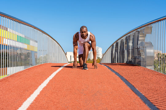 Athlete kneeling on running track on sunny day