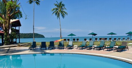 Resort swimming pool with sun beds next to the beach in Langkawi, Malaysia