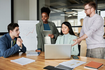 Business colleagues discussing with each other over laptop in meeting room at office