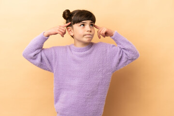 Little caucasian girl isolated on beige background having doubts and thinking