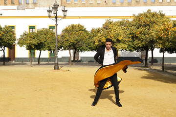 Young Spanish man in black shirt, jacket and pants, with dancing shoes, dancing flamenco with black...