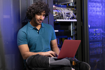 Technician using laptop sitting in server room