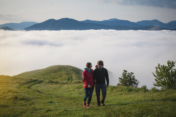 Fototapeta na wymiar Young Couple in Love Walks in Amazing Carpathian Misty Mountain Scenery
