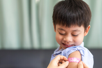 Portrait of happy smile vaccinated little asian kid boy children ages 5 to 11 years old posing show arm with medical plaster after Injection vaccine Covid-19 protection.coronavirus vaccination kid
