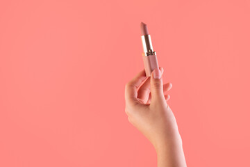 Female hand holding lipstick. Equipment for maquillage. Make-up and visagist. Place for text or creative design. Mockup style. Cosmetic and beauty concept. Isolated on pink.